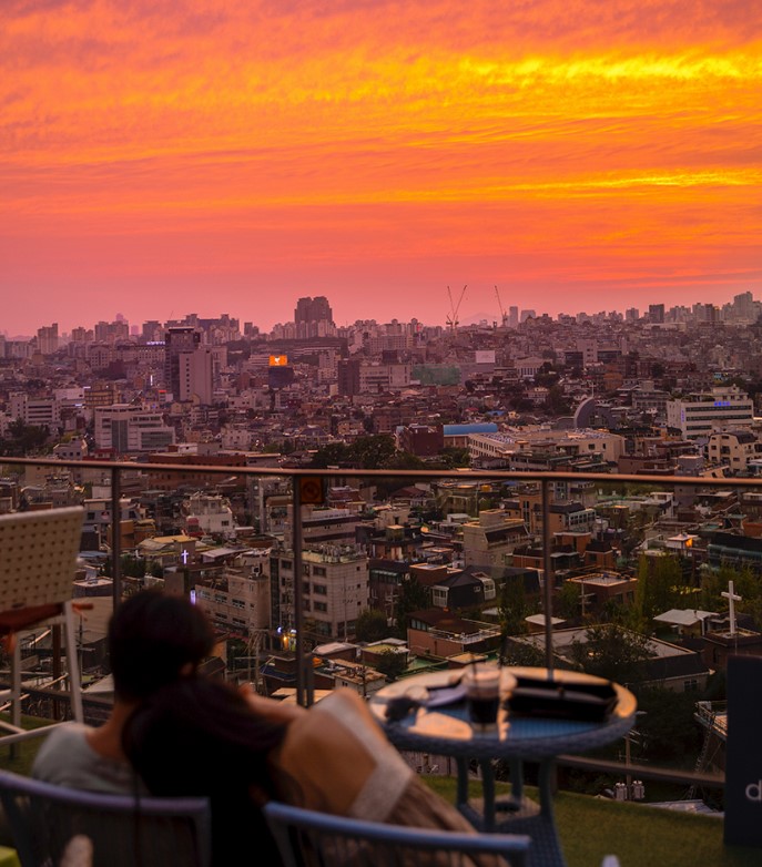 붉은 노을 및 두 사람이 벤치에 앉아있다.