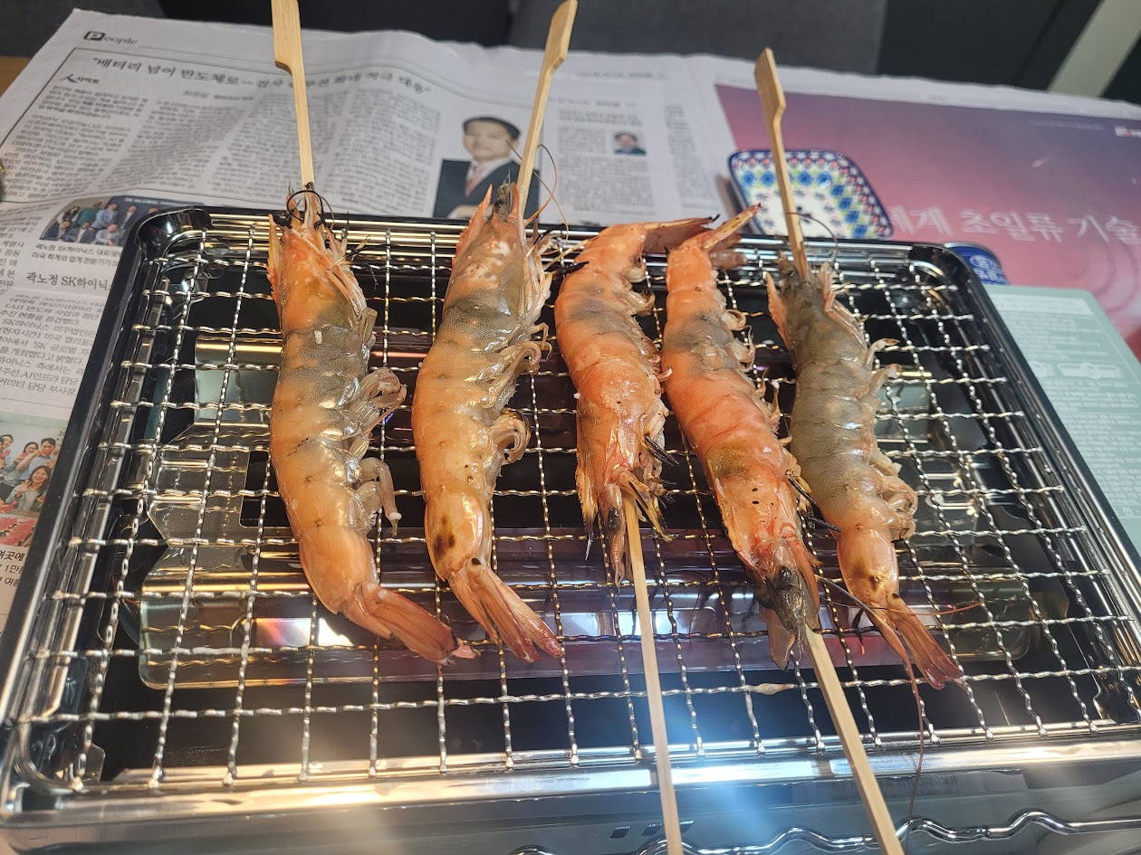 새우를 꼬치를 꼽아 구이바다에 굽는 모습