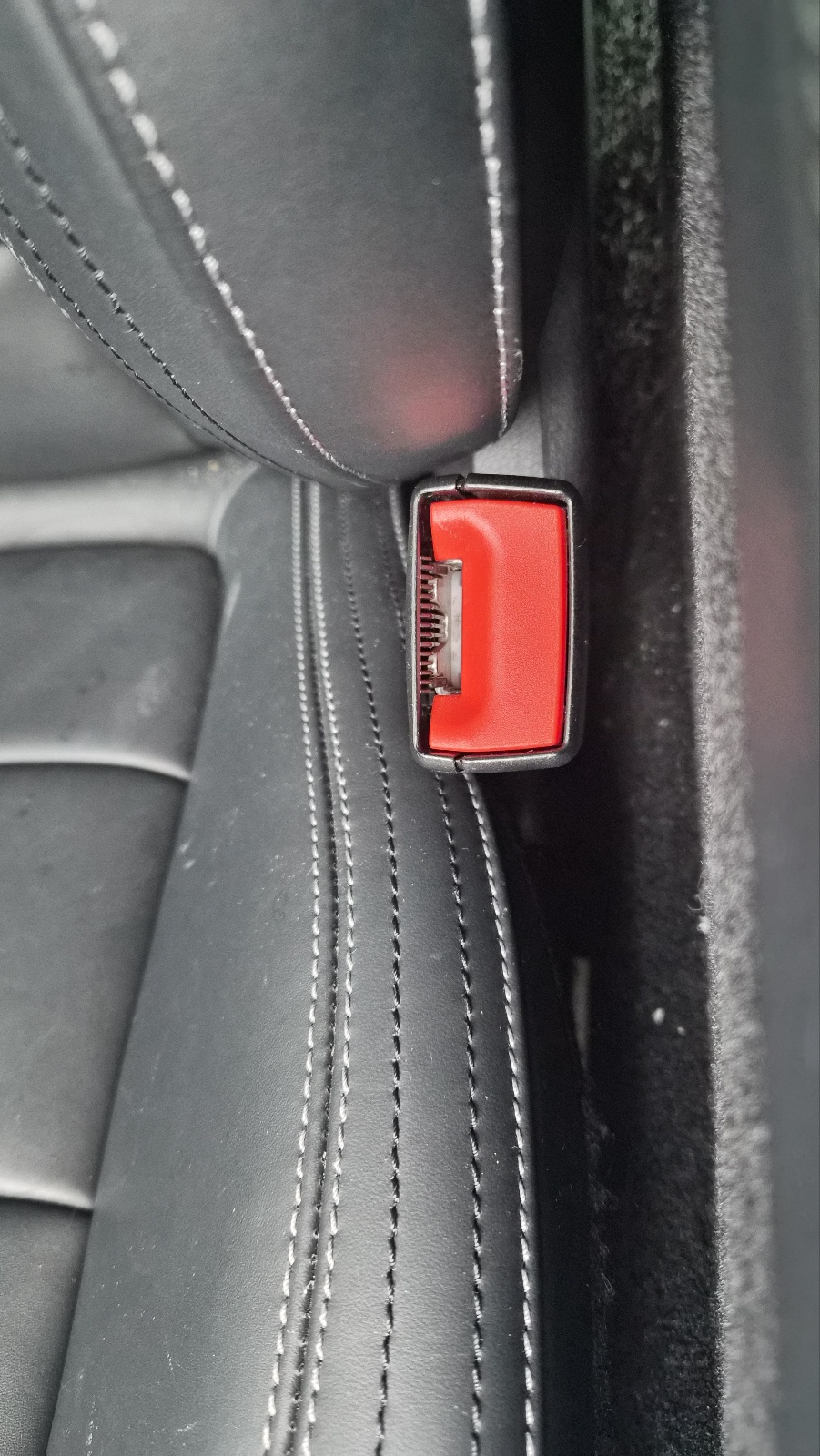 차량 좌석 옆에 위치한 빨간색 PRESS 버튼의 안전벨트 버클 소켓