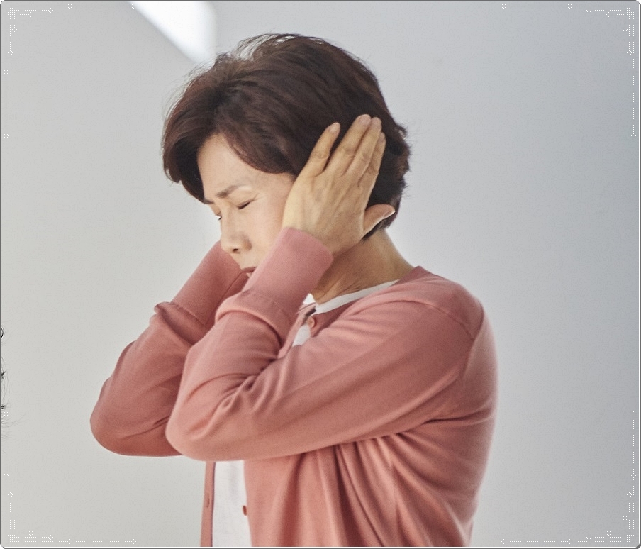 양쪽 귀를 막은 채 두 눈을 감은 중년 여성의 옆모습