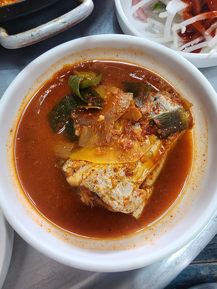 두툼한-갈치-한-토막이-빨간-국물에-담겨있고-대파가-올라가 있음