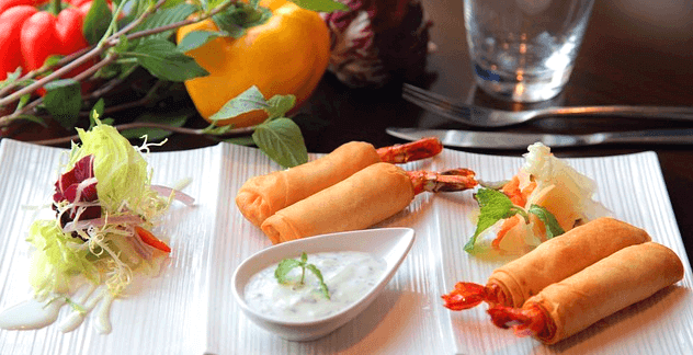 네모난 하얀 접시에 춘권 2개씩 있고 맨 왼쪽 접시엔 양배추 샐러드가 있다.