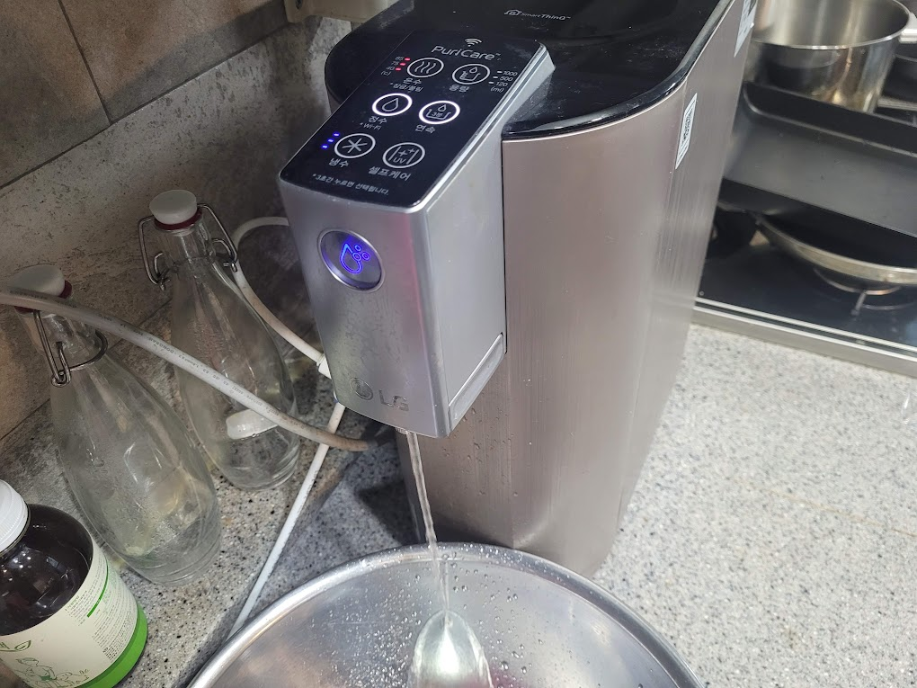 퓨리케어 정수기에서 물을 빼는 모습
