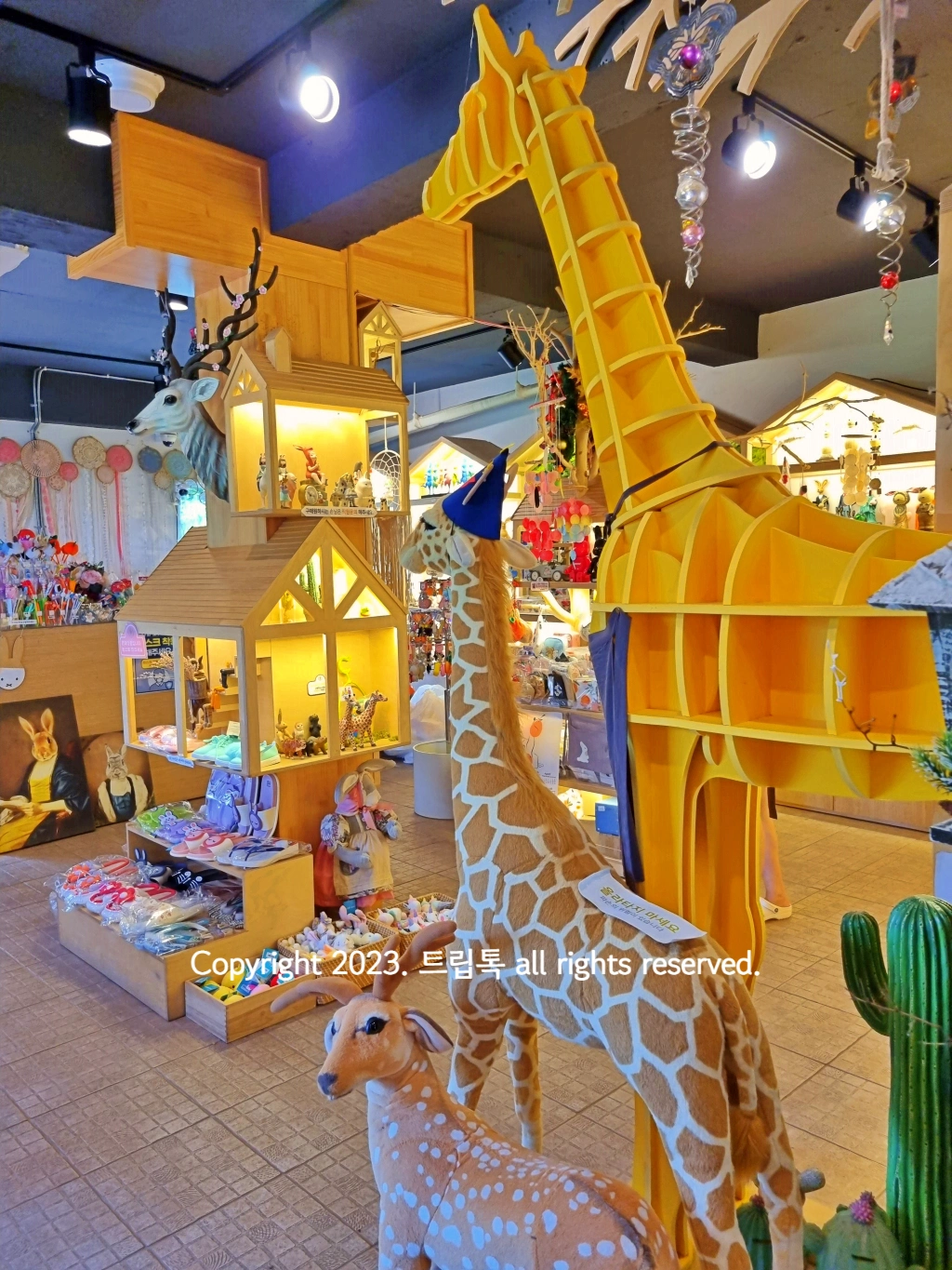 사슴과 기린인형이 커다랗게 있고&amp;#44; 그 앞에 작은 장난감이 많다.