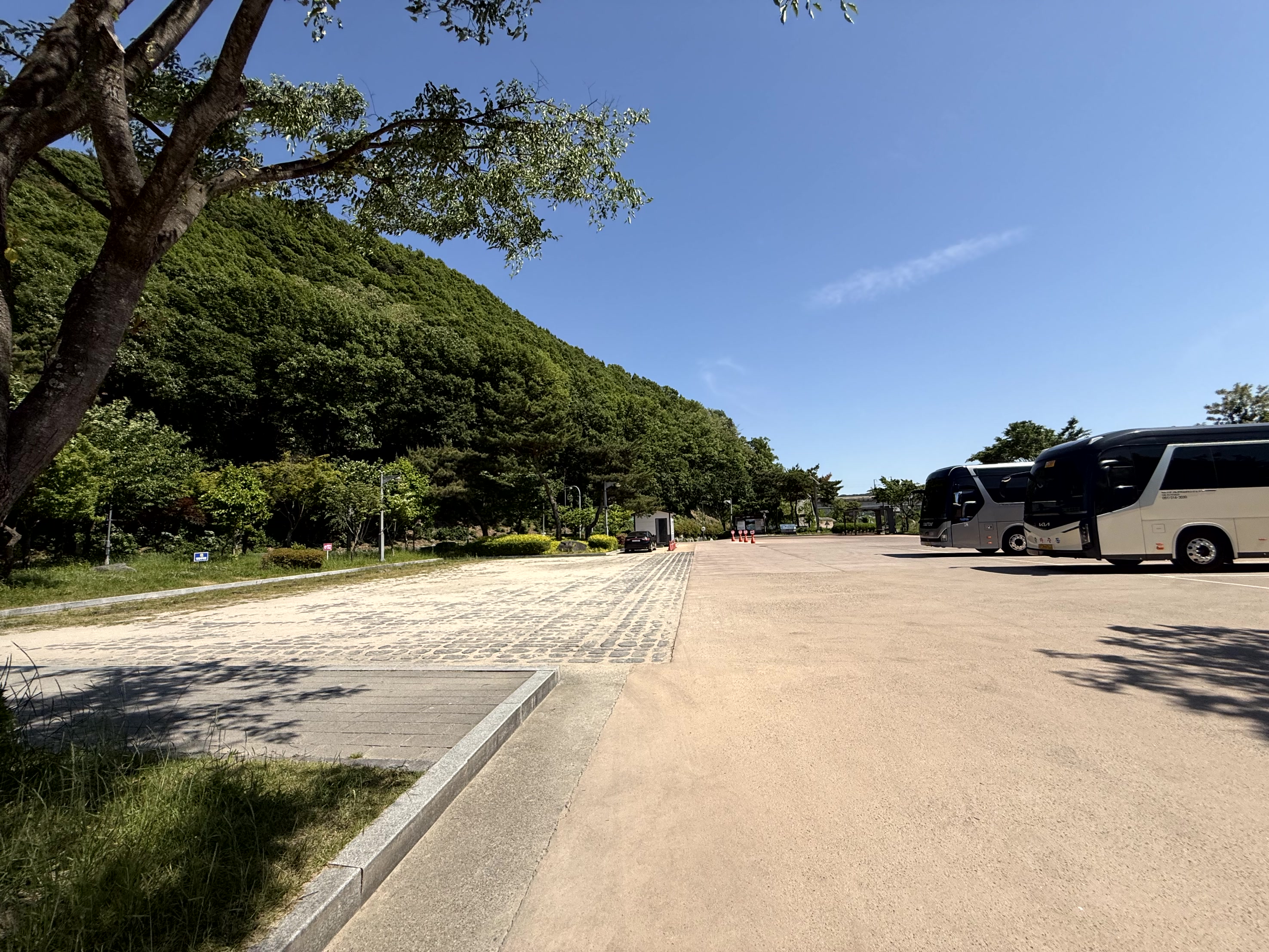 푸른 산을 배경으로 조성된 넓은 대형 버스 주차장과 주차된 버스들