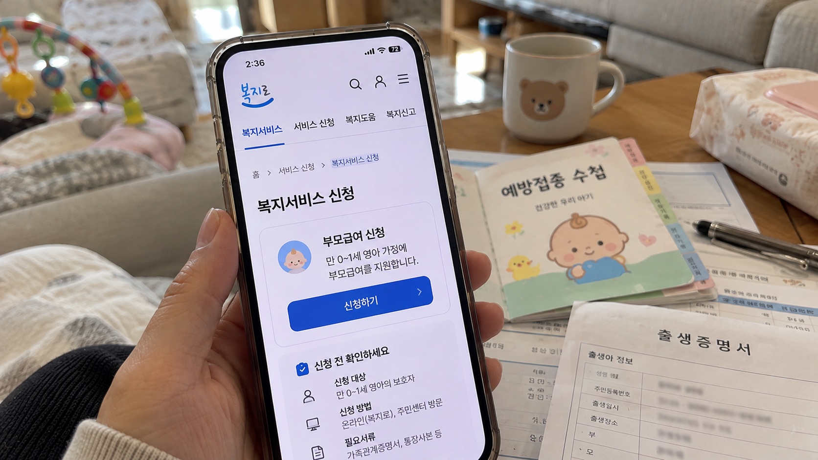 아기 장난감과 기저귀가 놓인 거실에서 스마트폰 맘카페를 보며 부모급여와 어린이집 보육료 지원을 고민하는 모습