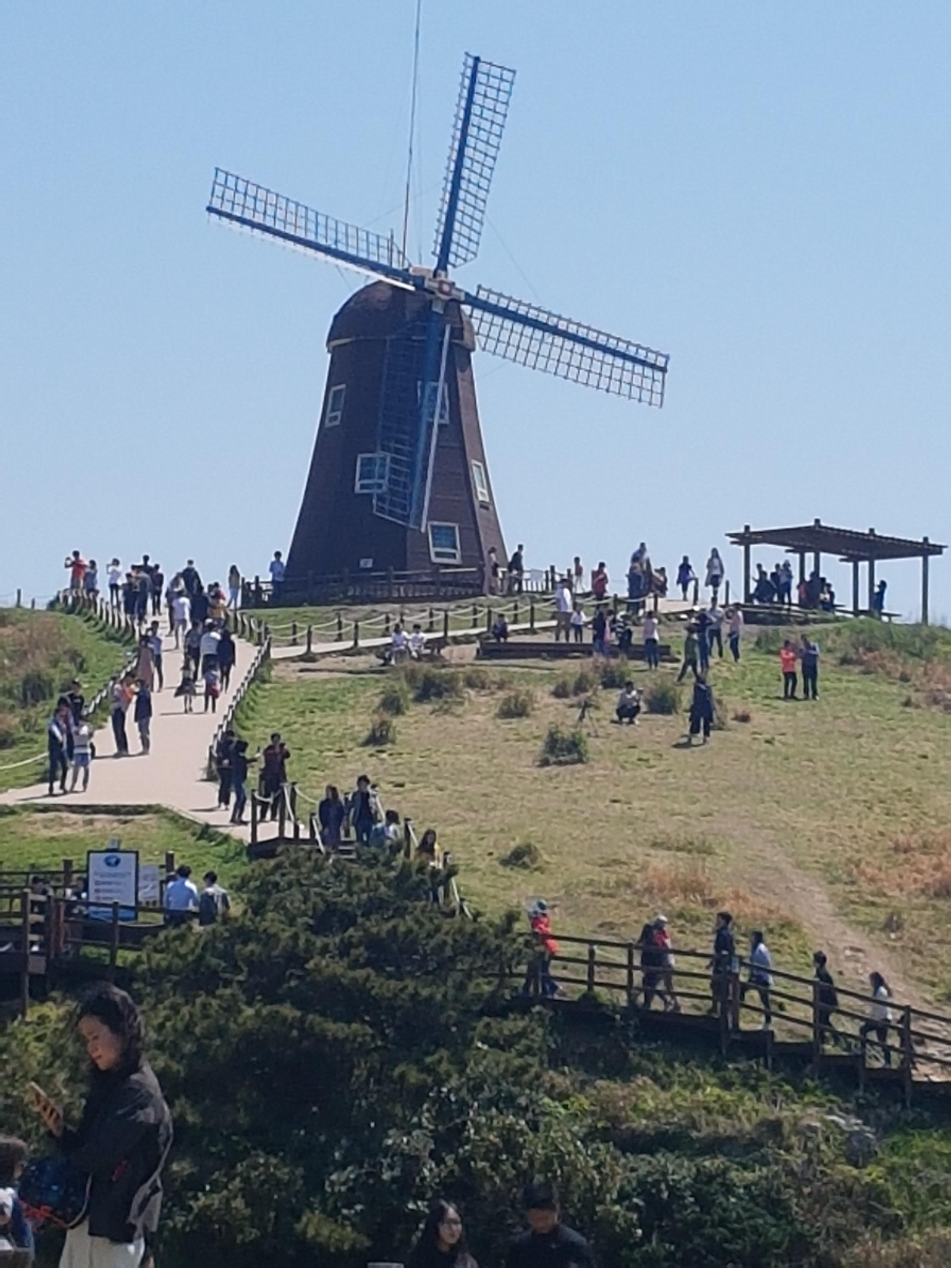 거제도 바람의 언덕 위에 있는 커다란 갈색 풍차와 푸른 하늘