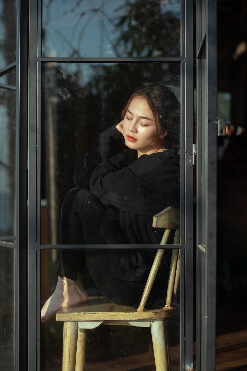 통 유리창 앞에 의자에 앉아 창에 기대어 있는 젊은 여성