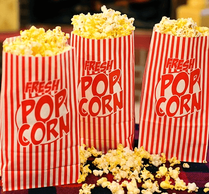 고소한 팝콘이 가득 담긴 종이봉지 3개가 나란히 서있다. 봉지는 빨간 세로줄이 가득 그려졌고 영어로 팝콘이라고 적혀있다.