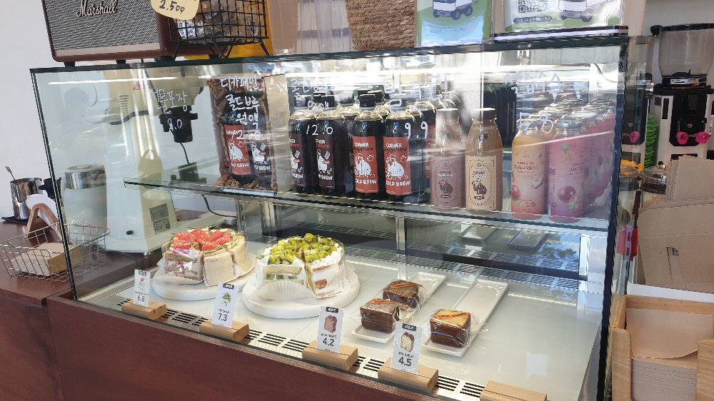 2단 유리 쇼케이스 상단에는 여러 음료가 하단에는 케익과 파운드가 있다.