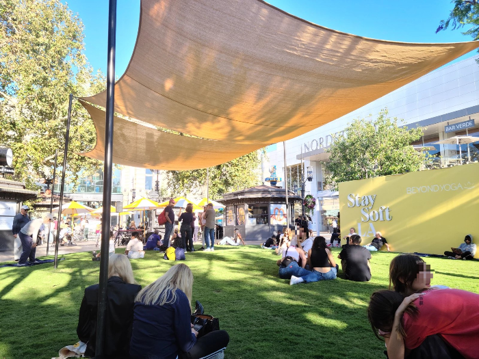 그로브 몰의 잔디 공원. 사람들이 그늘막 아래 잔디에 앉아 휴식하고 있다.