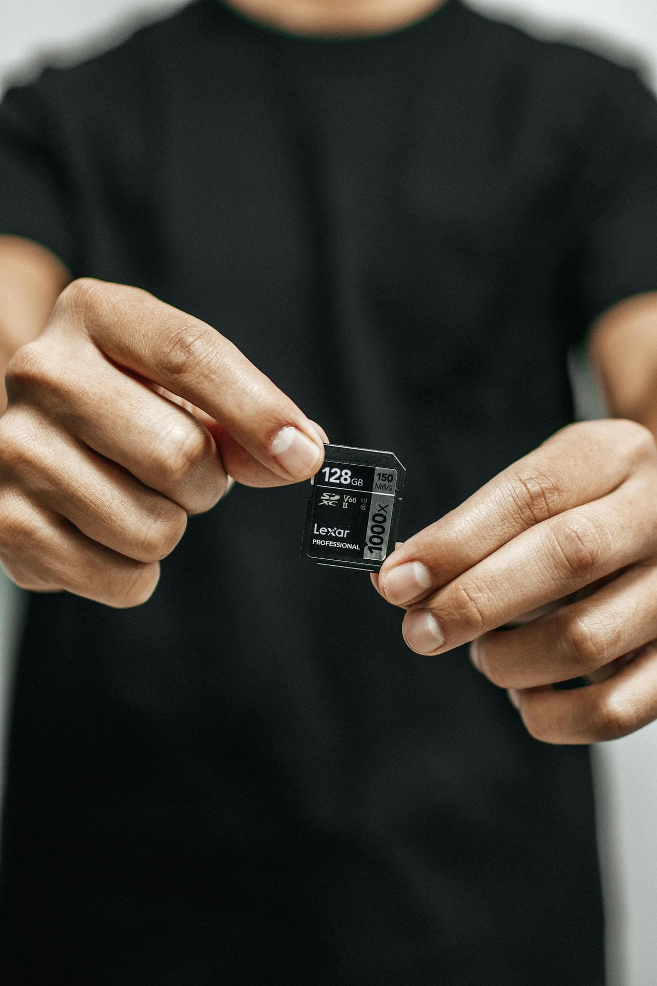 두 손으로 128GB Lexar SD카드를 들고 있는 사람의 근접 샷