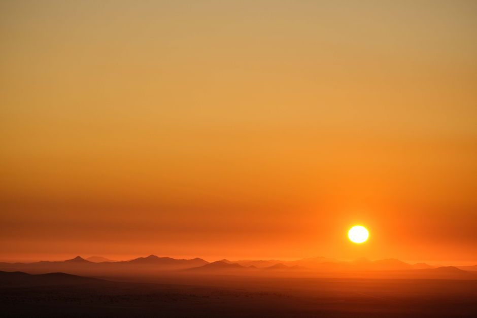 Captivating sunset over vast desert dunes, evoking tranquility with warm, golden hues.