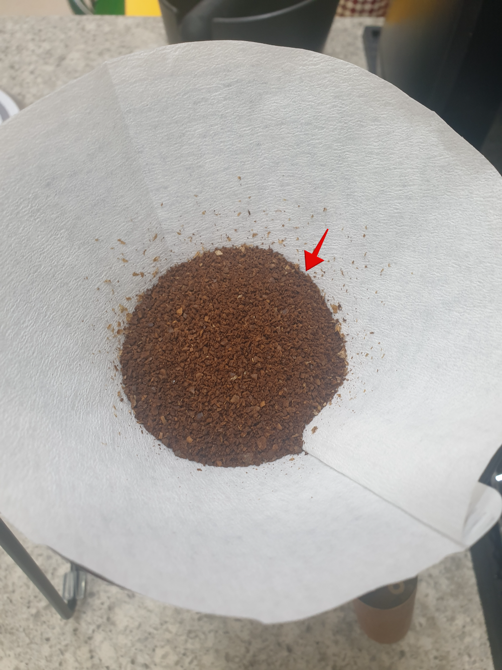 드리퍼 안에 원두가 들어있는 모습. 붉은 화살표로 원두가 담긴 양을 보여준다.