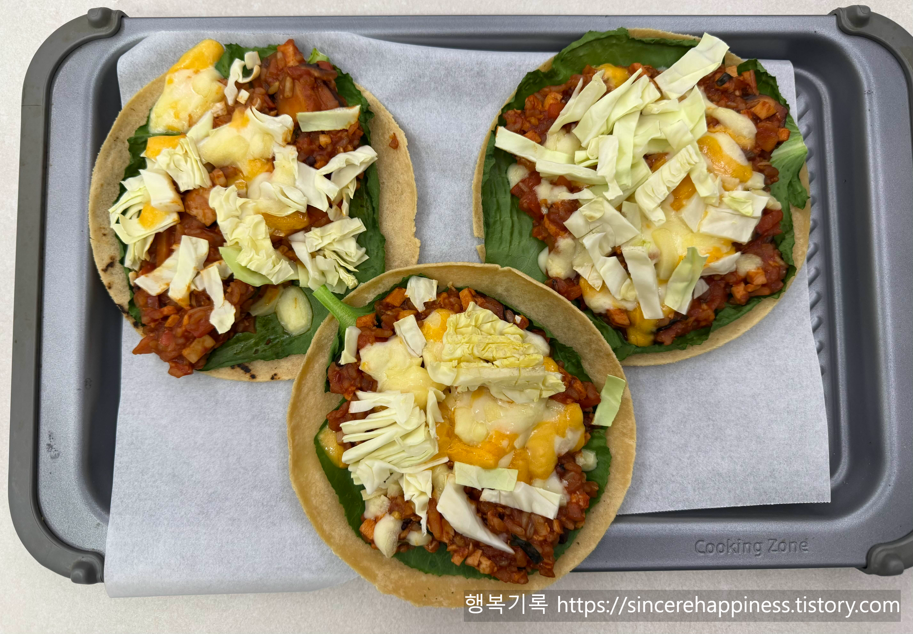 종이호일을 깐 팬 위에 올려진 에어프라이어 굽기 전 두부 또띠아 피자 3개