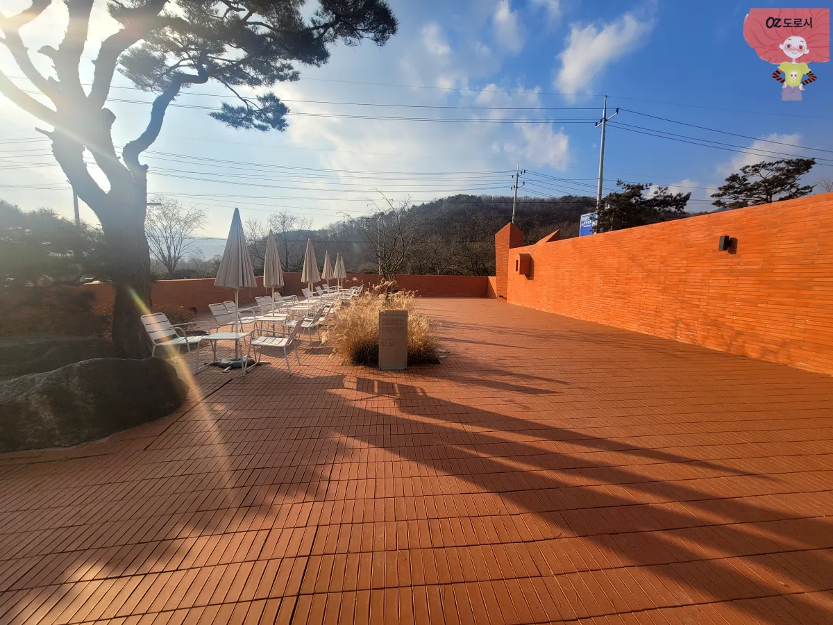 양평-한옥카페-하우스베이커리-예쁘게-쌓아올린-성벽과-파라솔이-달린-야외테이블-야외공간-이미지