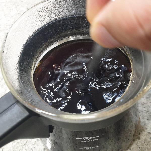 서버 안에 추출된 커피가 있다. 스푼으로 커피를 섞어주고 있다.