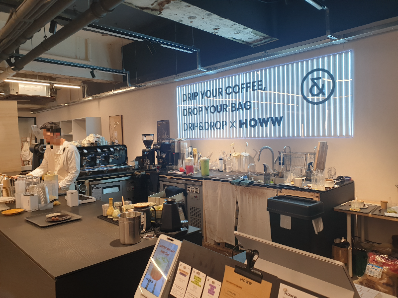 픽업대 뒷면 조명으로 'DRIP & DROP X HOWW'이 보인다.