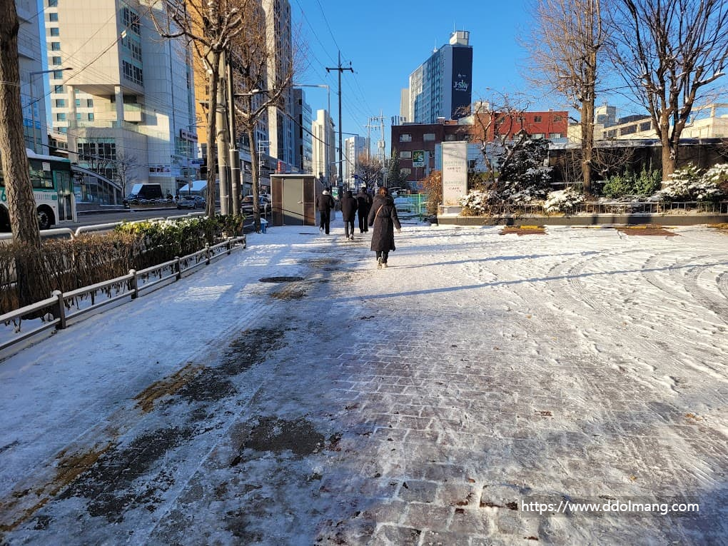 출근길 미끄러운 도로를 조심스럽게 걷는 사람들