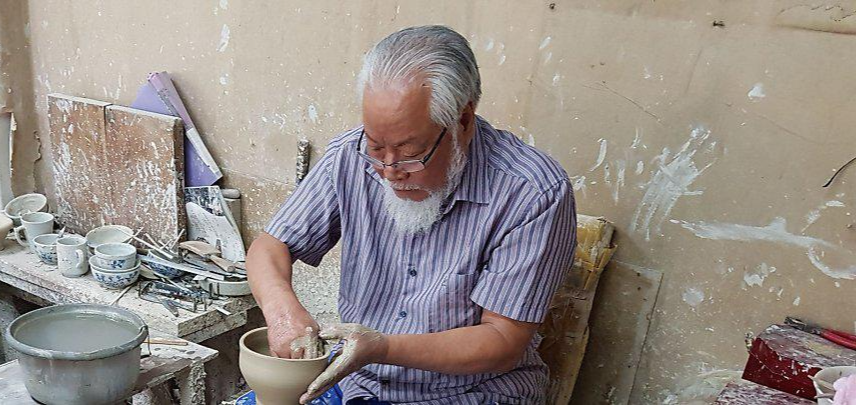 머리가 하얗게 센 노신사가 물레 위 도자기 빚기에 집중하고 있다.