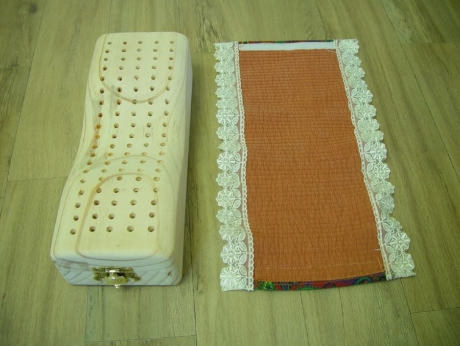 윗부분에 구멍이 많이 뚫려 있는, 잣나무로 만든 신침을 마룻바닥에 두고 그 덮개를 같이 나란히 옆에 두고 찍은 사진