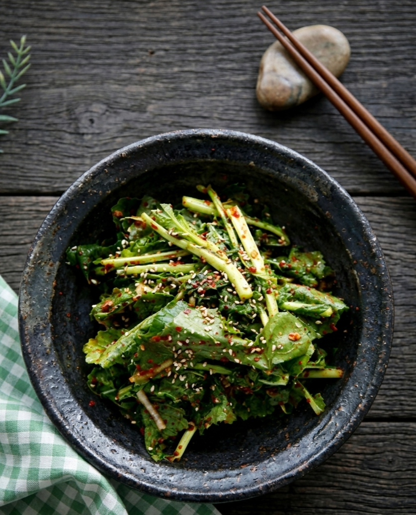 검정 도자기 그릇에 담긴 먹음직스러운 유채나물 겉절이.