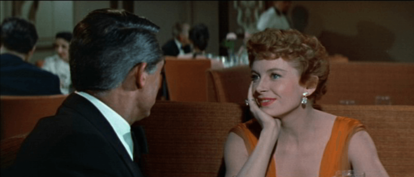 여자 주인공이 턱을 괸 채 웃으며 남자 주인공을 바라보는 모습