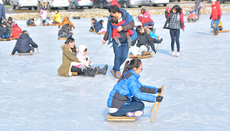 겨울 스포츠를 즐기는 사람들, 얼음 위에서 썰매를 타며 가족들과 함께 축제를 만끽하는 모습