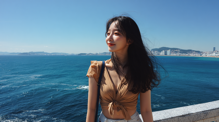 푸른 하늘과 바다가 어우러진 제주 해안에서 사진을 찍고 있는 젊은 여성