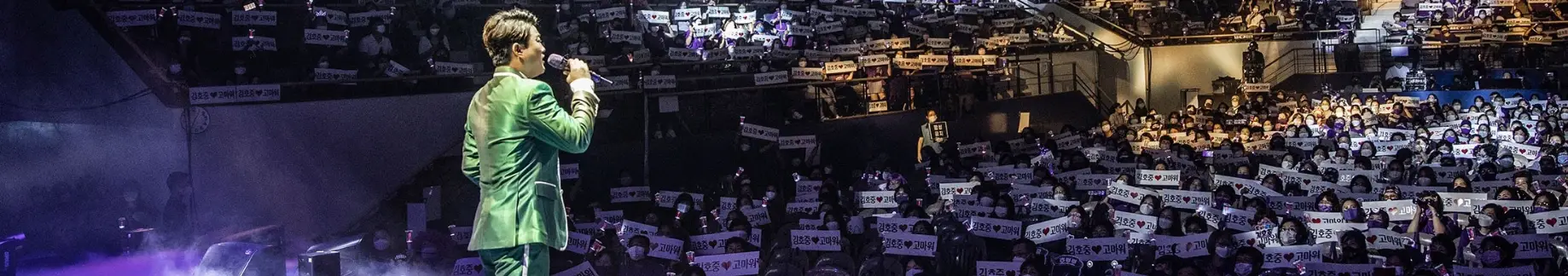 많은 관객들 앞에서 초록색 정장옷을 입고 노래하는 김호중