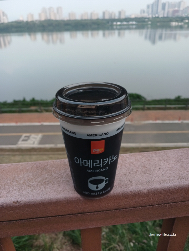 한강 배경 난간 위에 놓인 편의점 아메리카노 컵