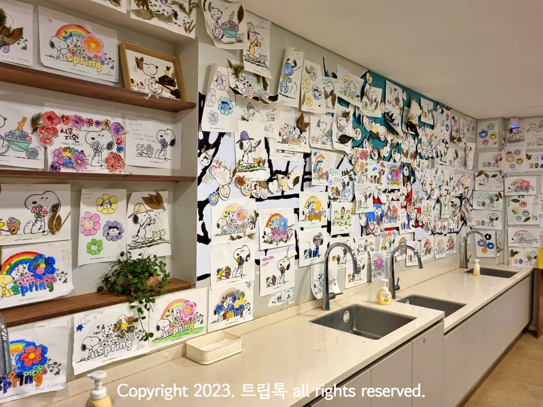 사람들이 색칠한 스누피 그림이 벽에 빼곡히 붙어져 있다