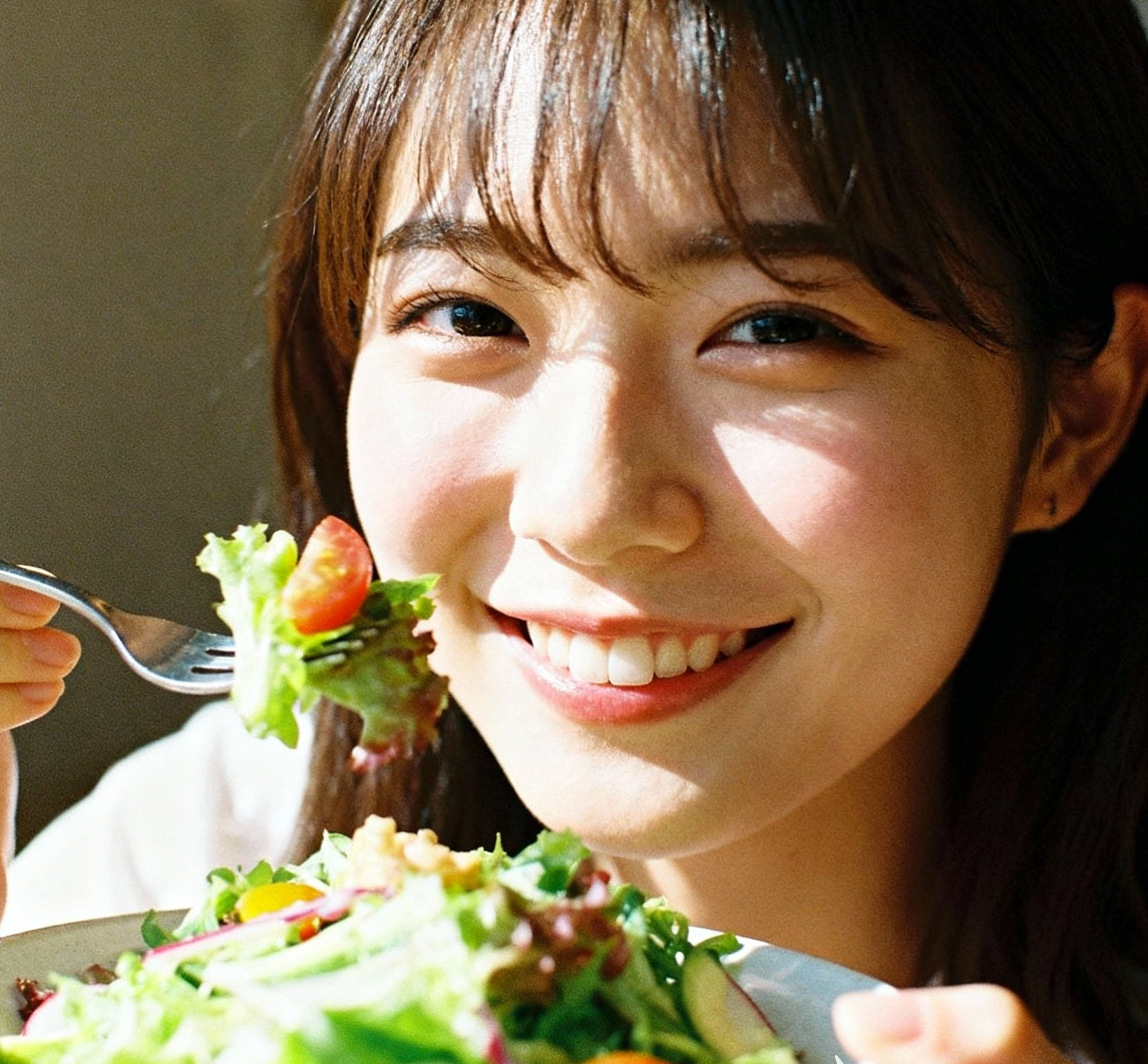 Smiling woman eating fresh vegetable salad with fork for healthy eating habits