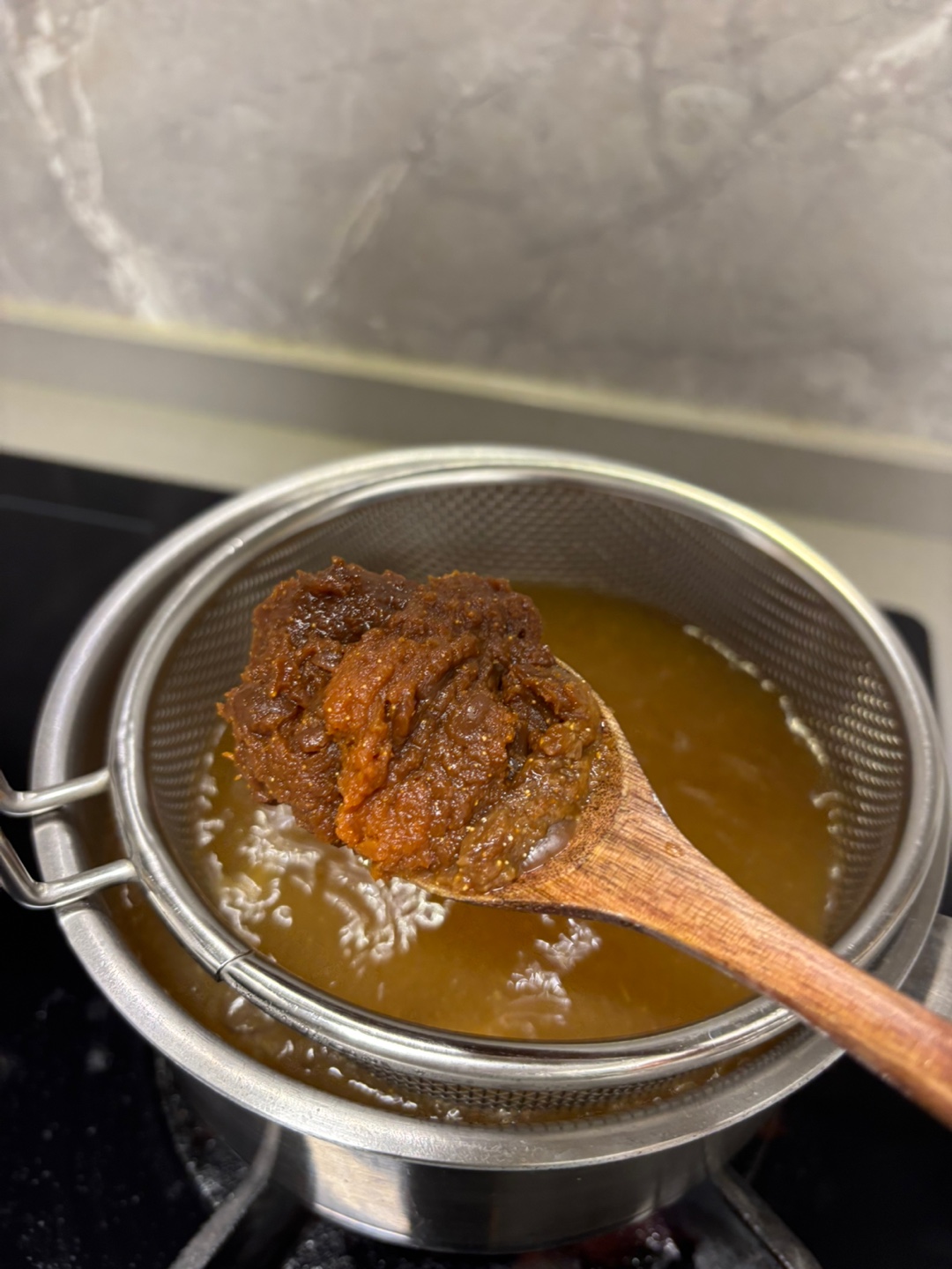 냄비에 망이 올려 있고 된장 한 숟가락을 넣으려고 준비 중이다