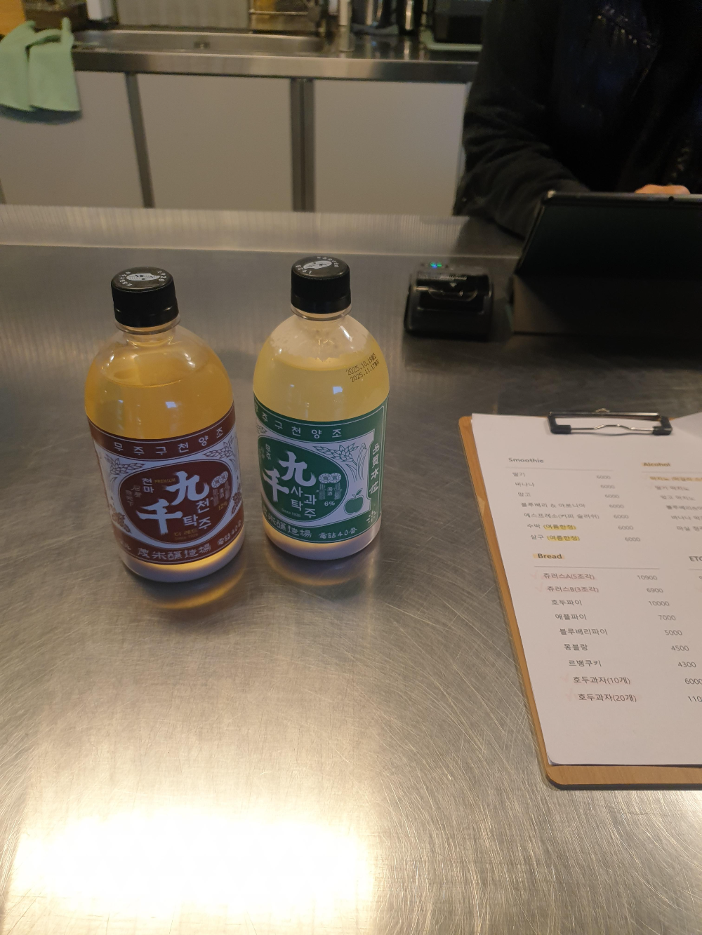 스틸 재질 테이블 위에 막걸리 병 두개가 있다. 왼쪽은 붉은 라벨 오른쪽은 초록색 라벨이다.