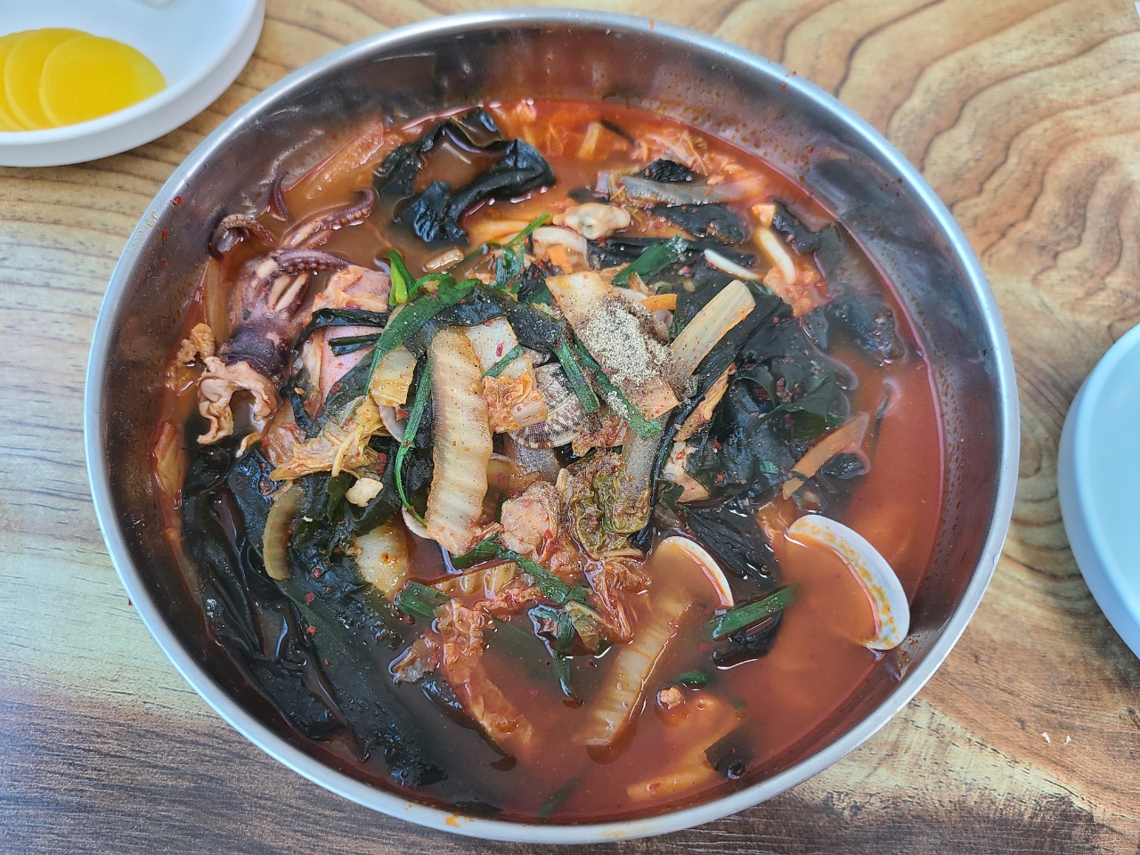 후추가 뿌려진 자그마한 통오징어 한마리와 푸짐한 미역등이 들어간 짬뽕