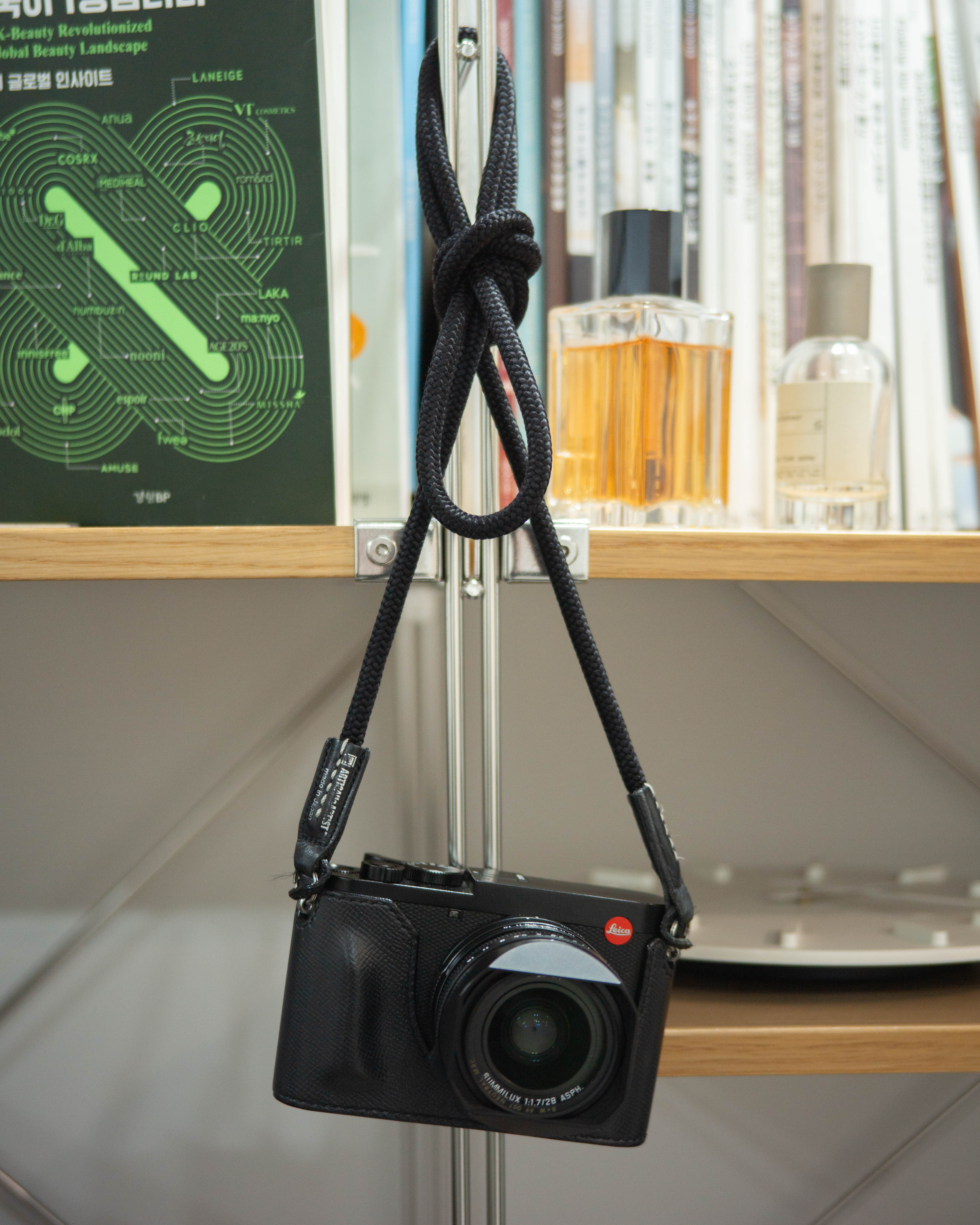 한 번 꼬아진 아티산아티스트 스트랩을 한 라이카 Q2가 벽에 걸려있다.