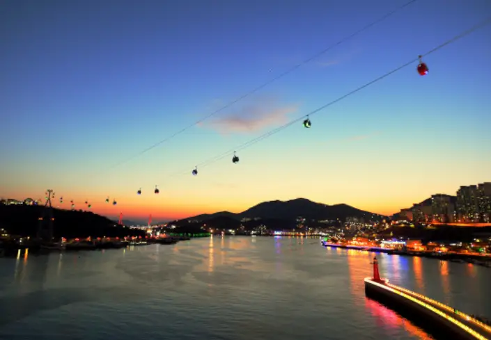 노을이 진 바닷가에서 운행중인 해상케이블가 여러대