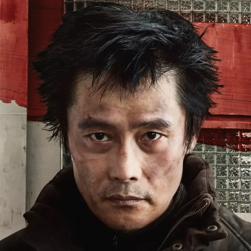 황궁아파트를 배경으로 허름한 복장 겨울 복장과 부시시한 머리를 하고 있는 콘크리트 유토피아 영화의 김영탁