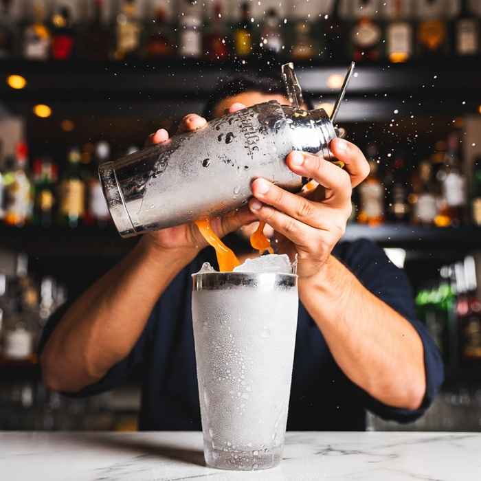 얼음과 함께 오렌지 주스를 강렬하게 흔들어 섞는 브롱크스 칵테일 제조 과정