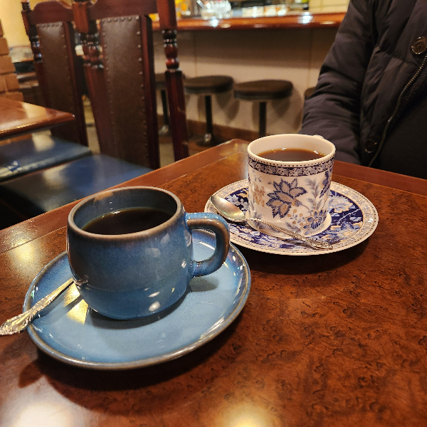 파란색과 흰색 커피잔과 접시. 접시에는 은색 스푼이 함께 놓여있다.