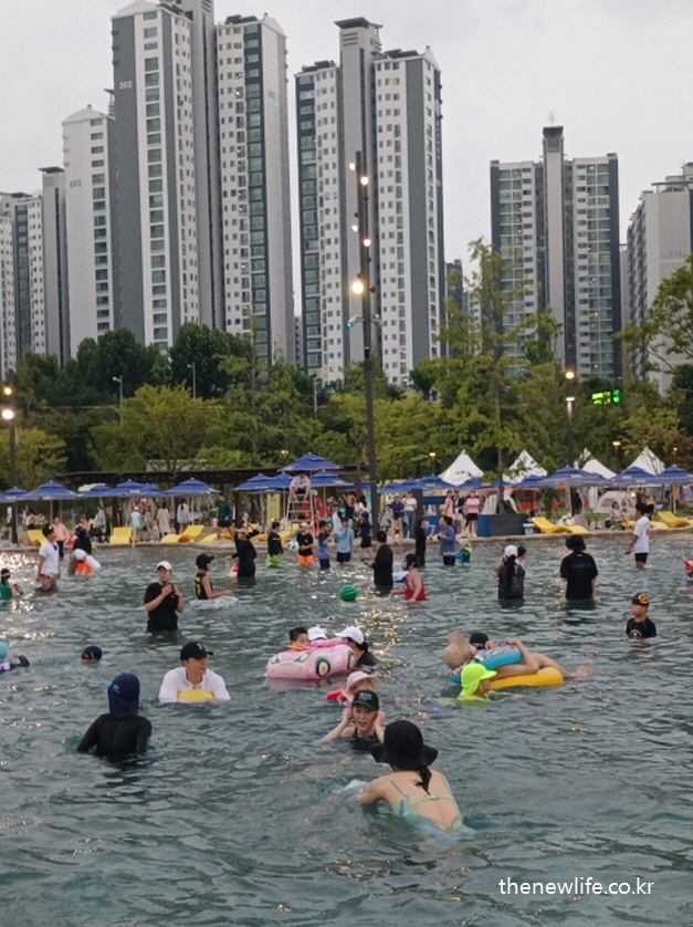 잠실 한강공원 물놀이장 중앙에서 아이들과 함께 노는 부모들 모습 &ndash; 수영장 전체 풍경 포함