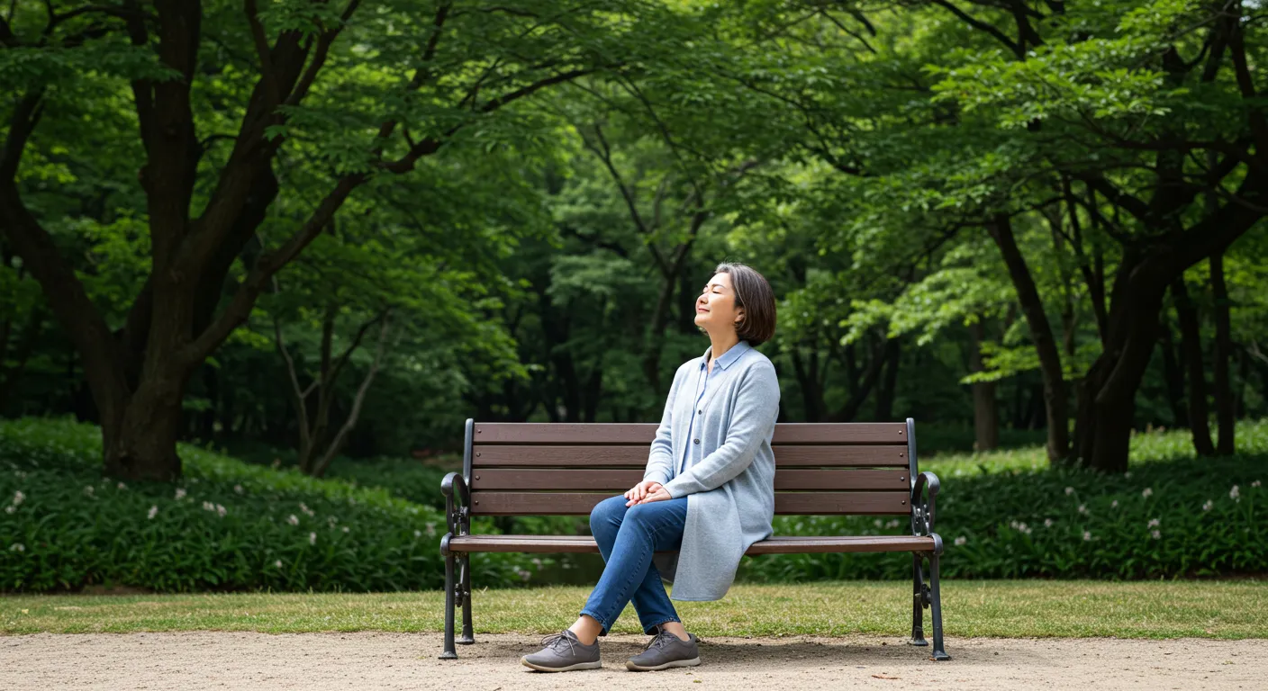 숲길 벤치에 앉아 평화로운 표정으로 자연의 향기를 느끼고 있는 중년여성