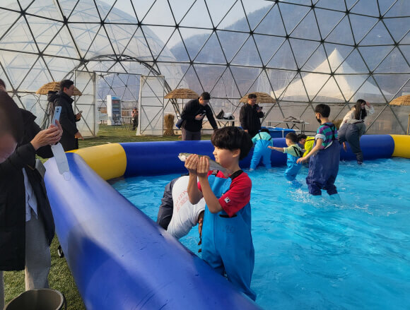 대형욕조에 들어가 송어를 맨손으로 잡아 올리는 모습