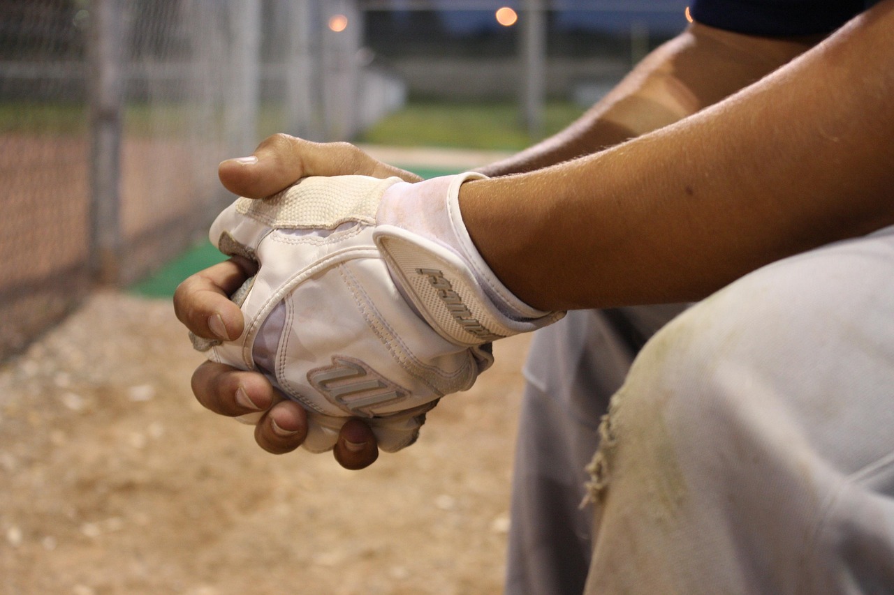 A father helping his son put on batting gloves before a Little League tryout.