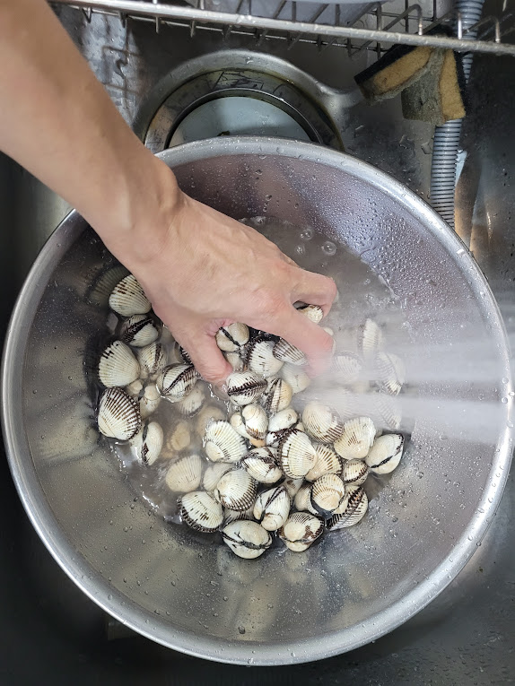꼬막을 양푼에 담아 손으로 씻는 장면