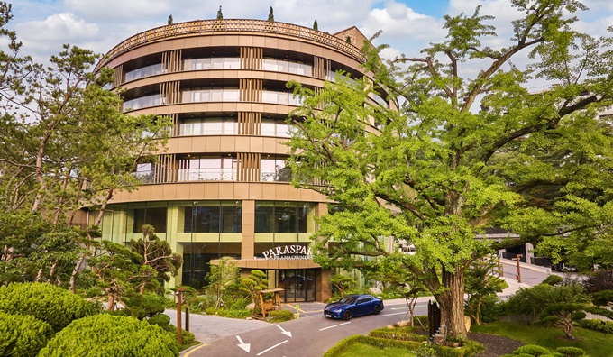 서울 우이동에 위치한 파라스파라 서울 호텔 전경. 자연 속에 자리 잡은 모던한 건물 외관과 푸르른 나무가 조화를 이루며 고급스러운 분위기를 자아낸다.