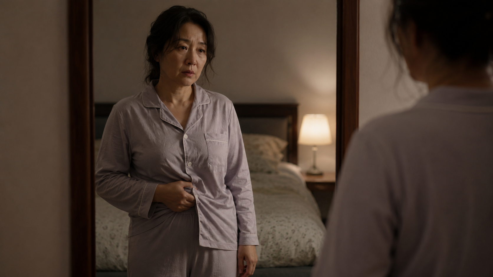 수면 부족과 갱년기 호르몬 변화로 인해 늘어난 뱃살(거미 체형)을 거울로 보며 고민하는 50대 중년 여성