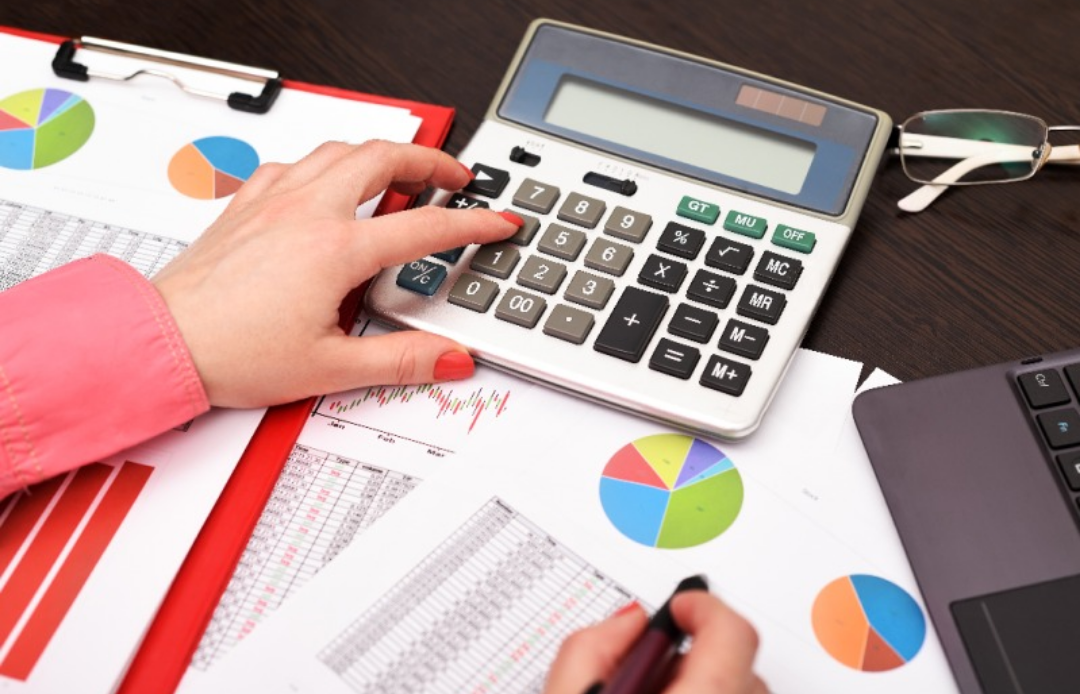 한 여성이 그래프가 적힌 종이를 보며 계산기를 두드리고 있다.