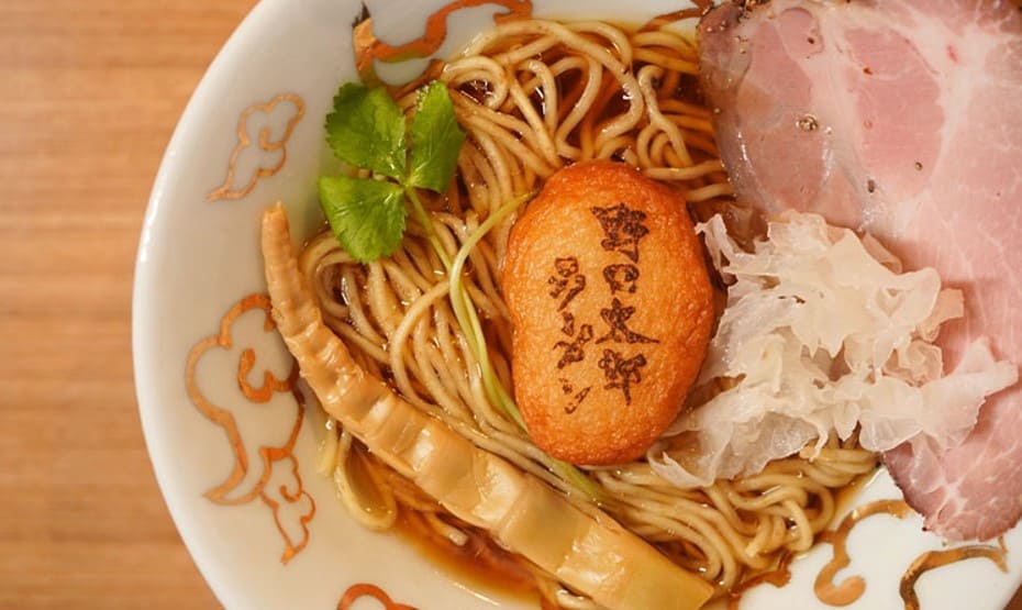 갈색 국물의 라면과 햄과 오뎅이 라면위에 올라가 있다